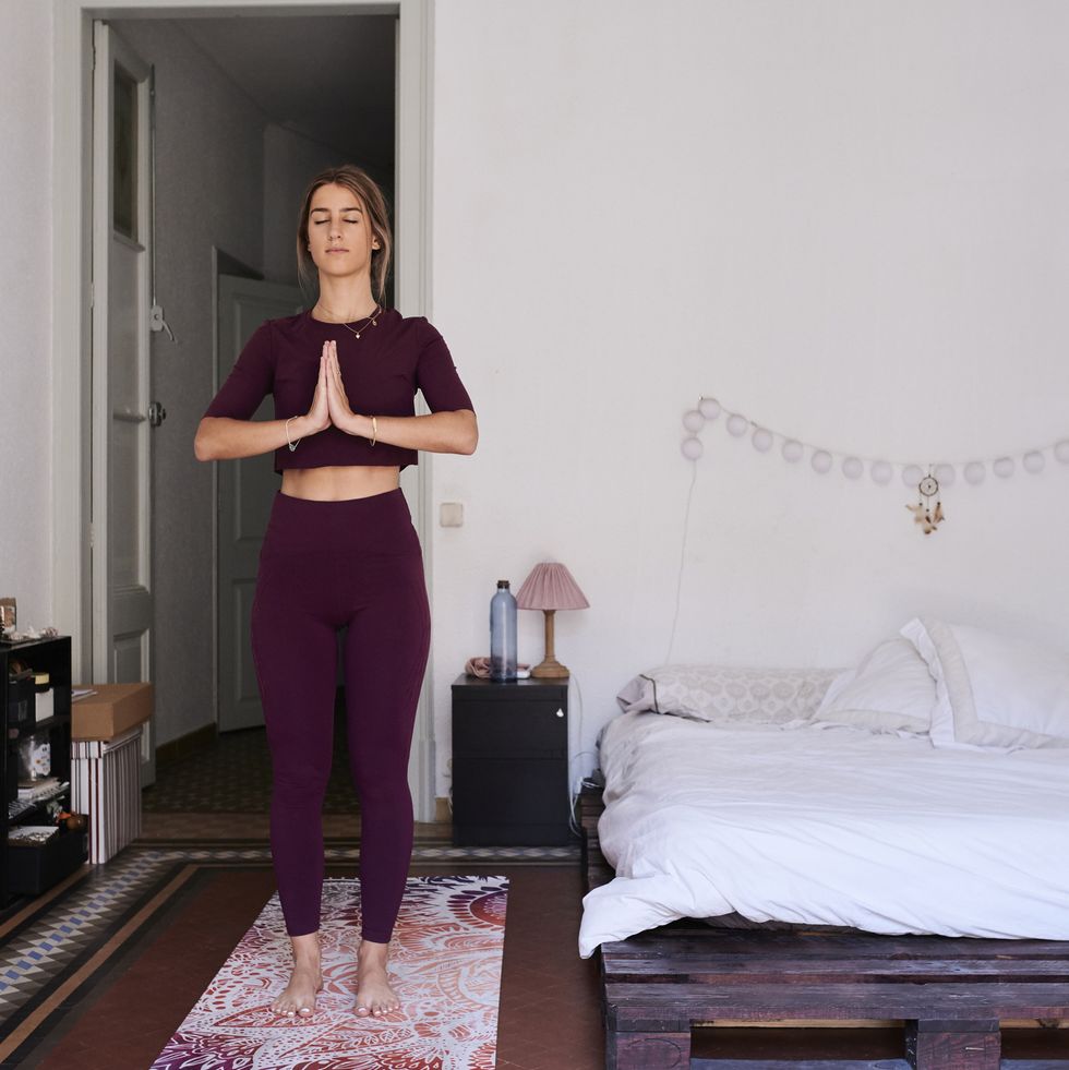 young brunette woman practising yoga in student dorm