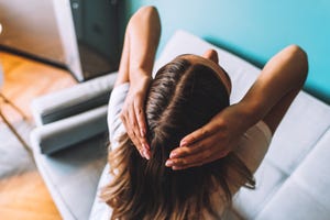 young brunette woman showing her hair, hair roots, hair loss or dry scalp