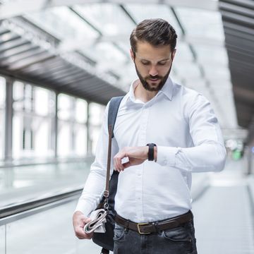 young businessman on moving walkway checking the time