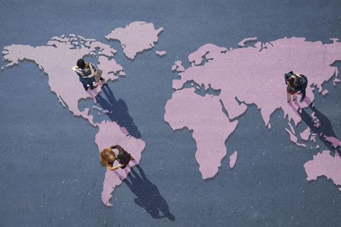 young businesspeople hugging, while standing on world map, painted on asphalt