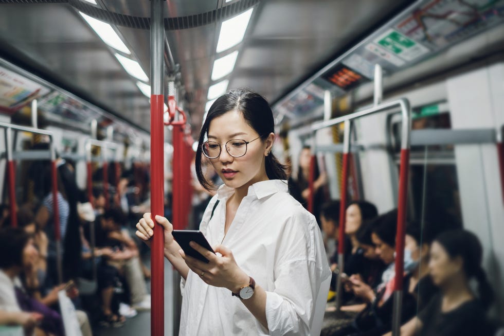 Young businesswoman looking at smartphone while riding on subway