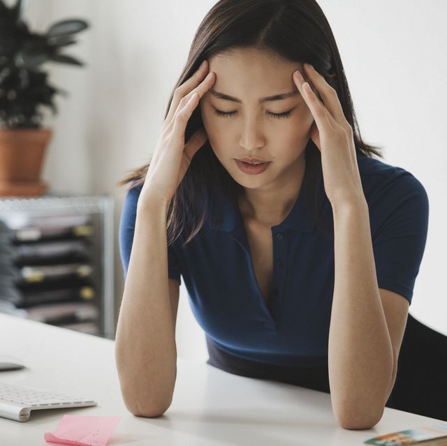 young businesswoman suffering from headache at desk in office
