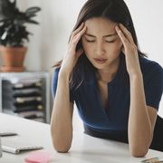young businesswoman suffering from headache at desk in office