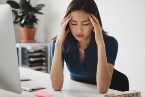 young businesswoman suffering from headache at desk in office