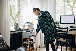 young businesswoman using computer printer at home office