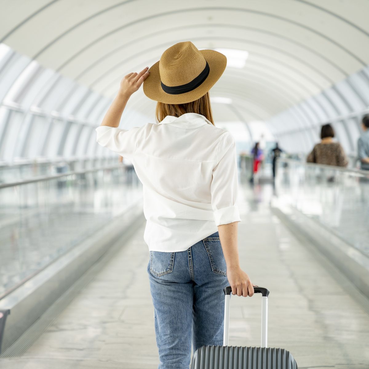 young casual female traveler with suitcase at airport