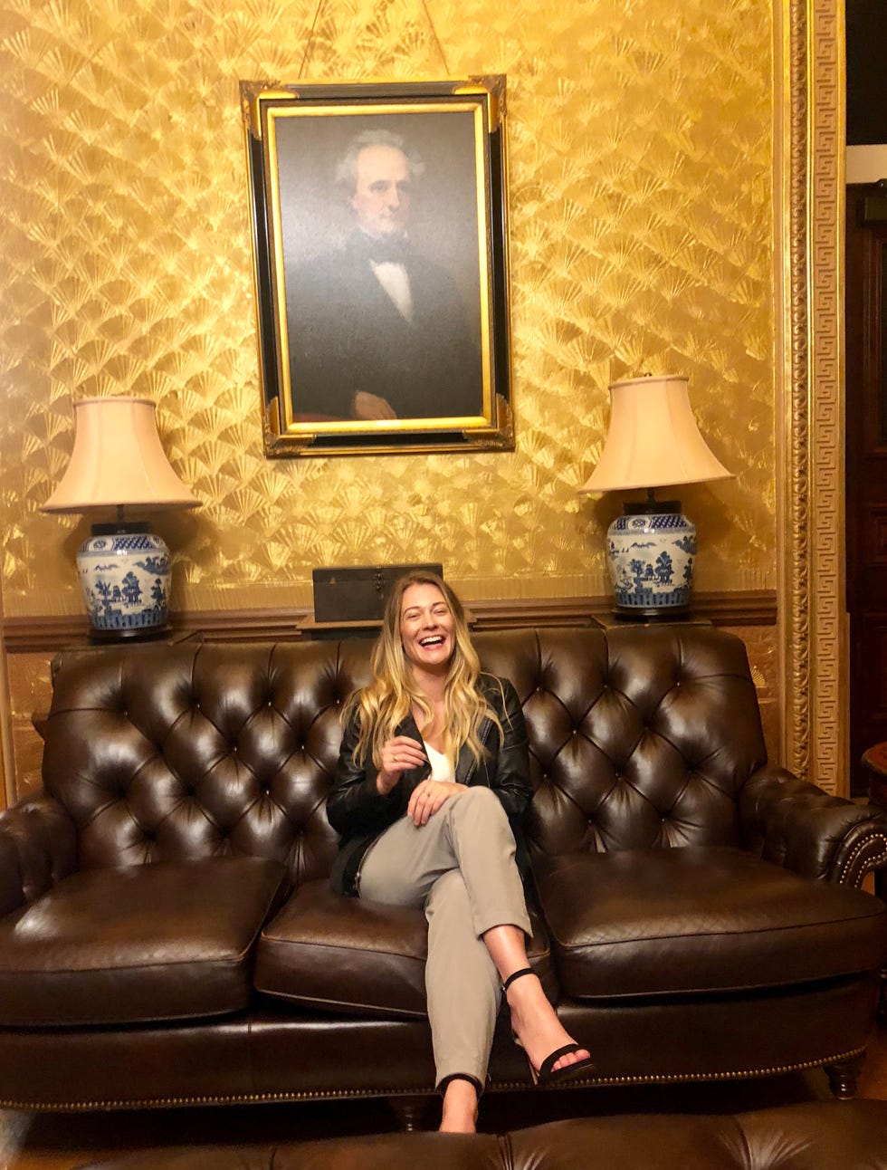 a person sitting on a brown leather sofa in a richly decorated room
