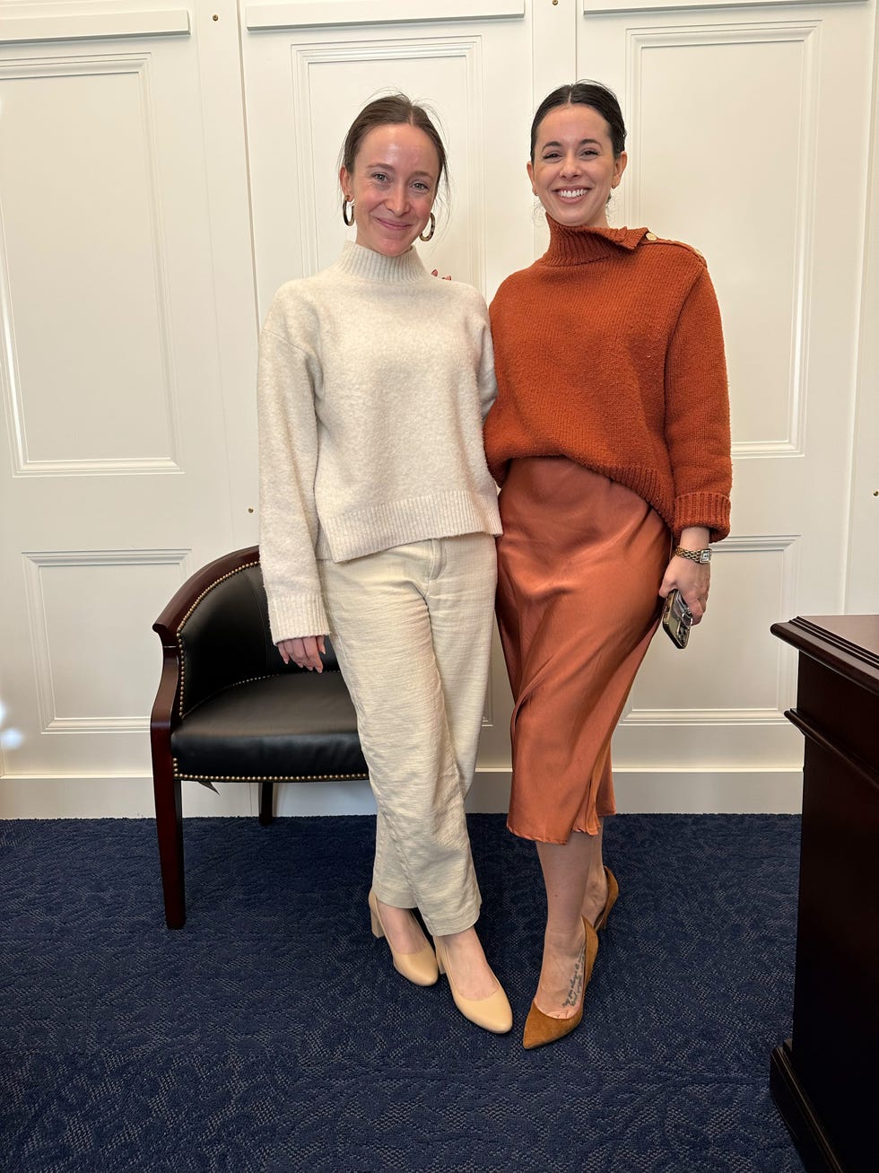 two women posing together in a formal indoor setting