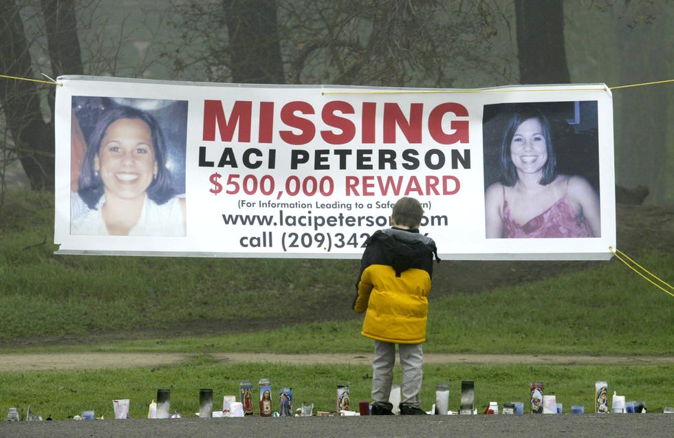 child stops to look at a makeshift memorial and large hanging poster for missing california woman laci peterson