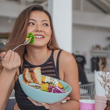 young chinese woman eating healthy vegan salad in a cafe