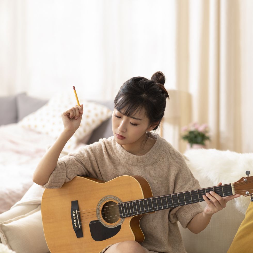 birthday in quarantine- Young woman playing guitar at home