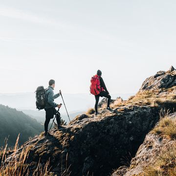 young couple backpack up a mountain summit