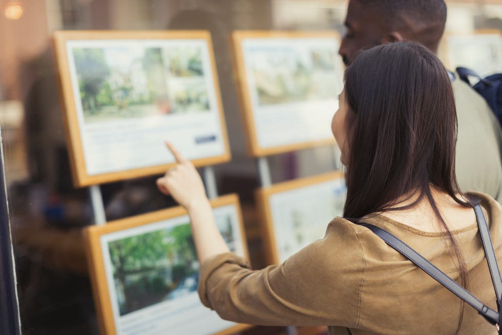 Young couple browsing real estate listings at storefront