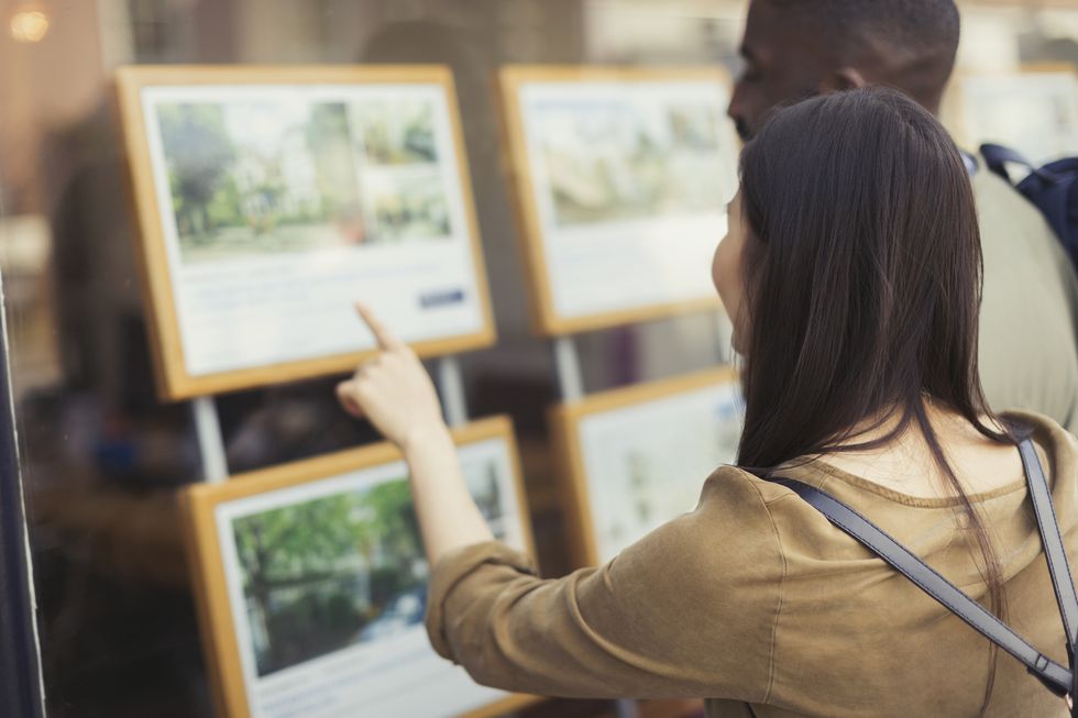 Young couple browsing real estate listings at storefront