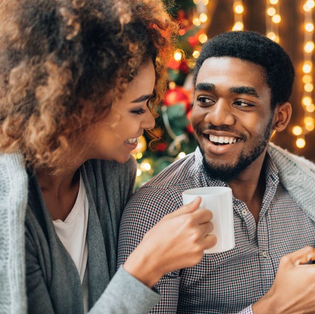 young couple drinking coffee at christmas tree