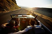 young couple driving convertible at sunset after learning how car refinancing works