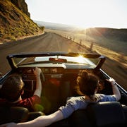 young couple driving convertible at sunset after learning how car refinancing works