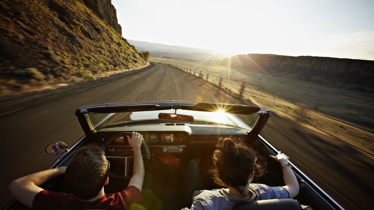young couple driving convertible at sunset after learning how car refinancing works