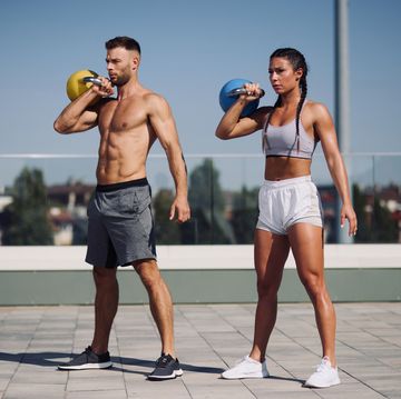 young couple exercising with kettle bell weights outdoors