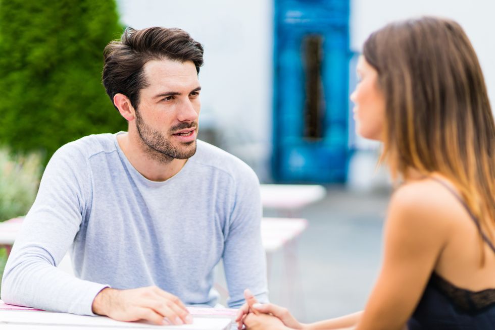 young couple having conversation at outdoor bar