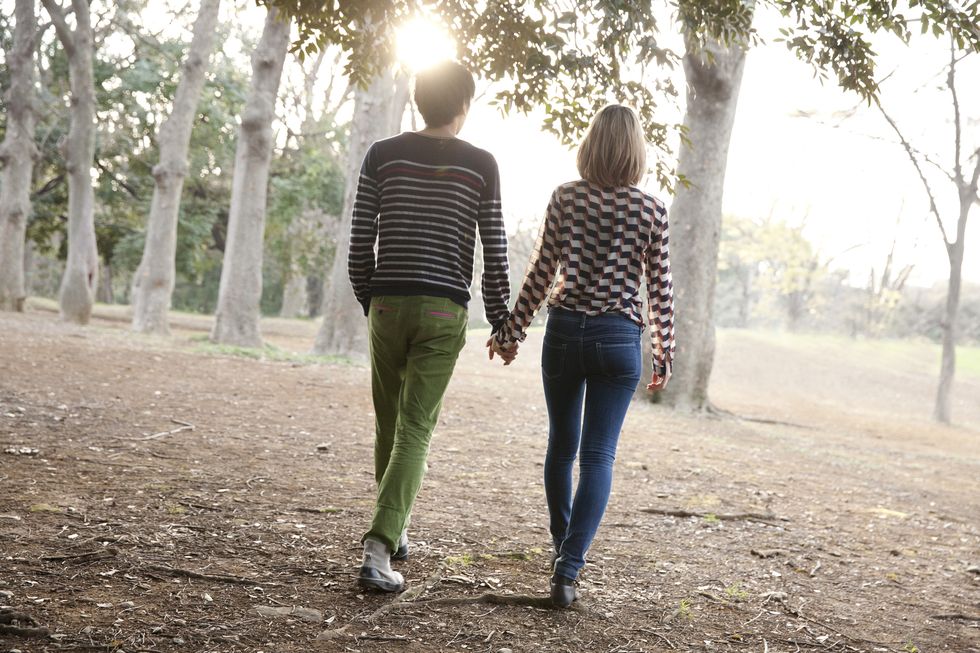 Young couple holding hands in park,rear view