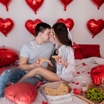 young couple with takeout dinner on bed