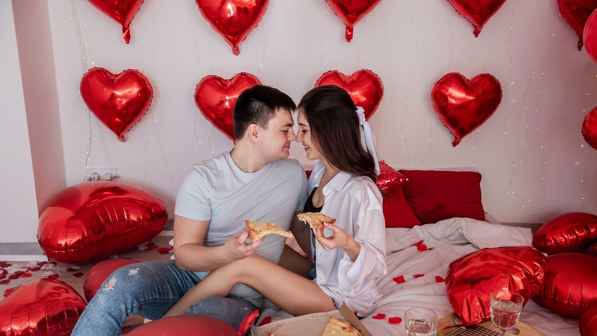young couple with takeout dinner on bed