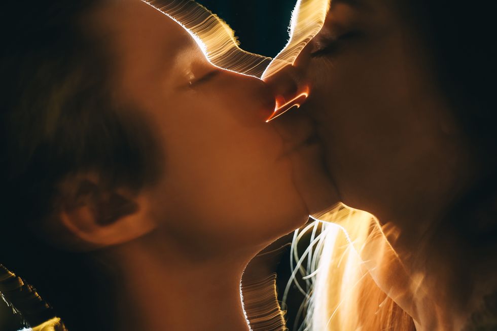 young couple in love kissing in dark with back lit close up