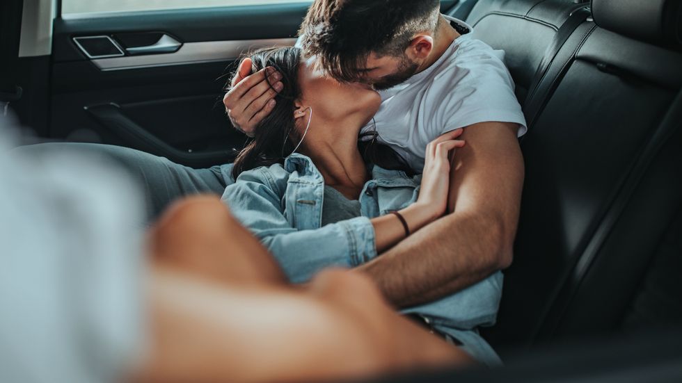 young couple kissing in the back of the car