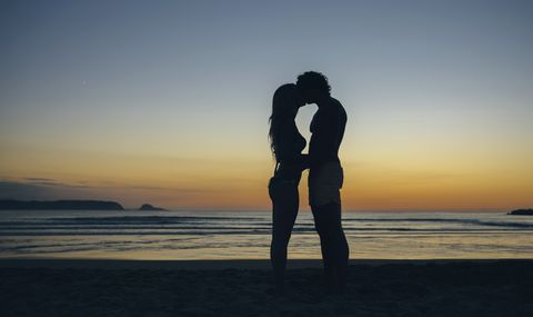 Young couple kissing on the beach at dusk