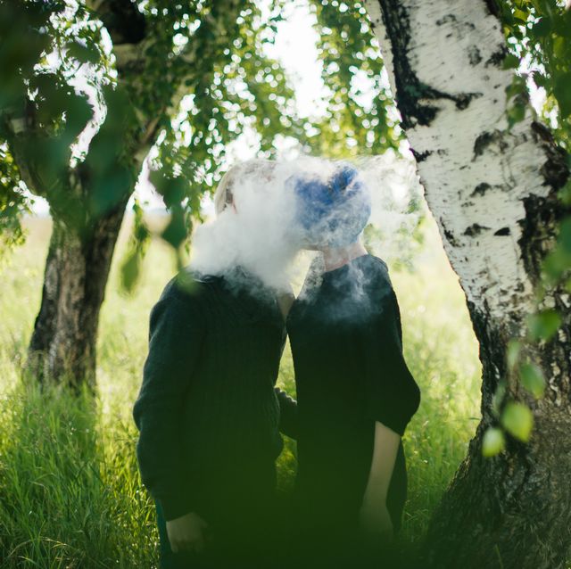 Young Couple Kissing While Exhaling Smoke