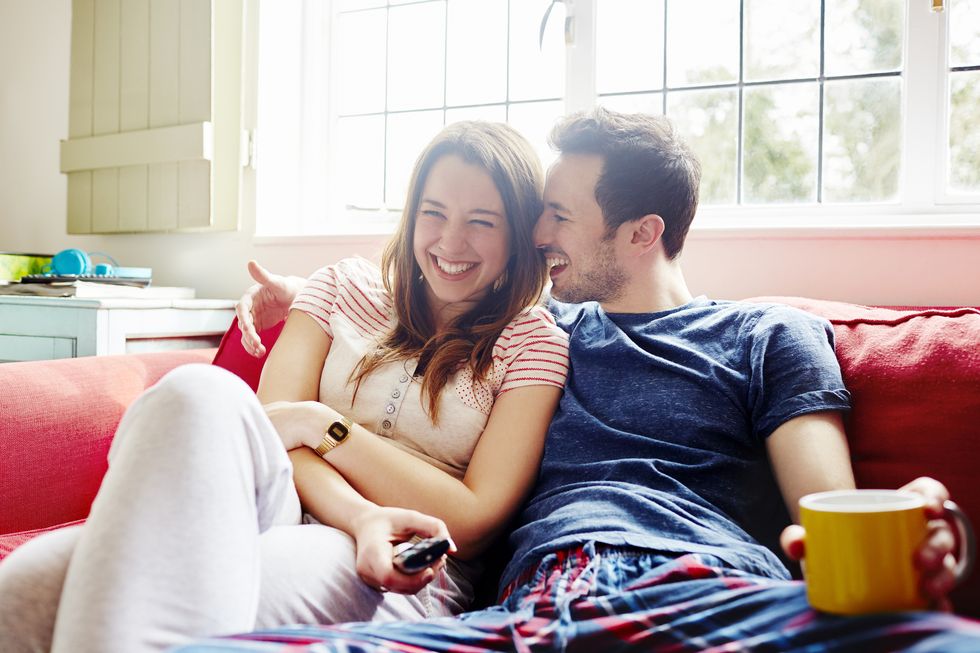 Young couple laugh together as they relax on sofa