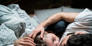 Young couple lying in bed embracing face to face