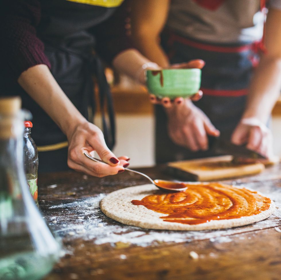young couple making fresh pizza in kitchen
