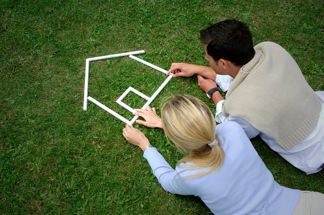 Young couple making house shape with rulers on grass