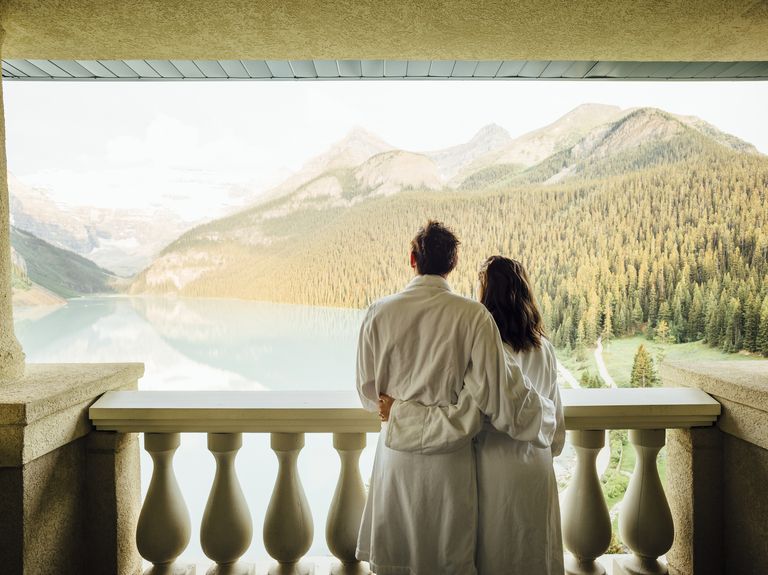 young couple overlooking lake louise on balcony, banff national park, alberta, canada