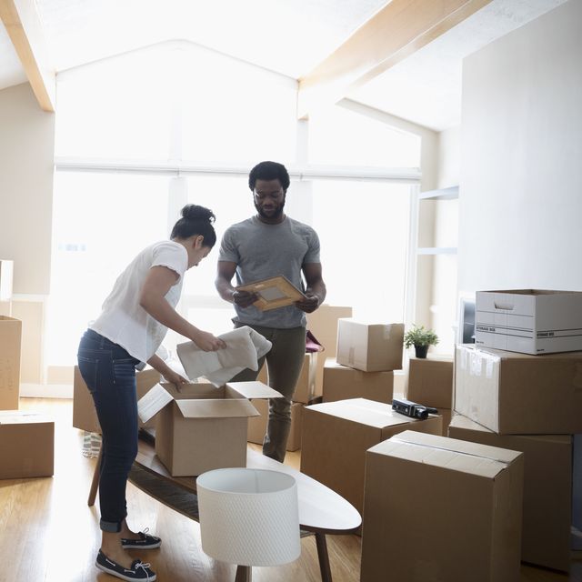 Young couple packing belongings in cardboard boxes, moving house