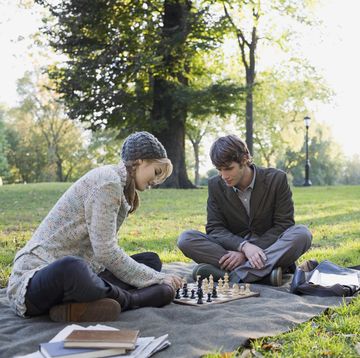 young couple playing chess in park