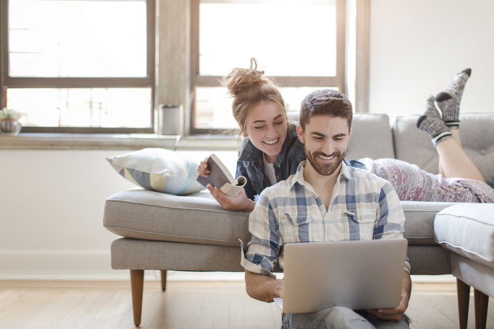 young couple relaxing at home, looking at laptop