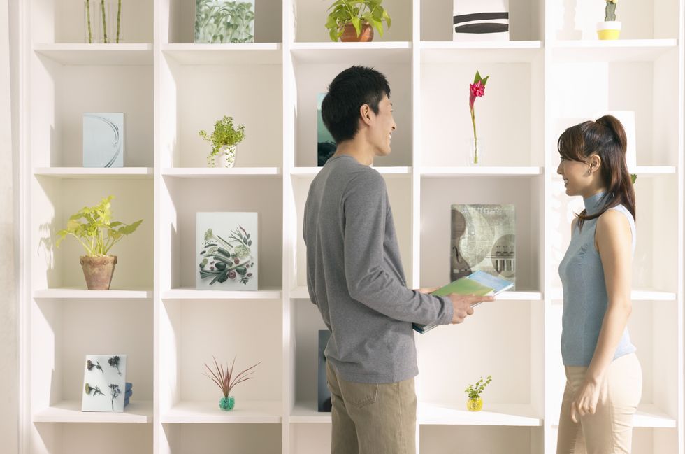 young couple stand by a shelving unit in their home, talking