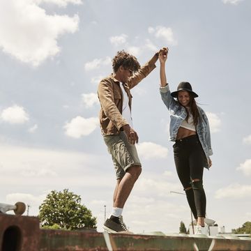 young couple standing on wall, raising arms