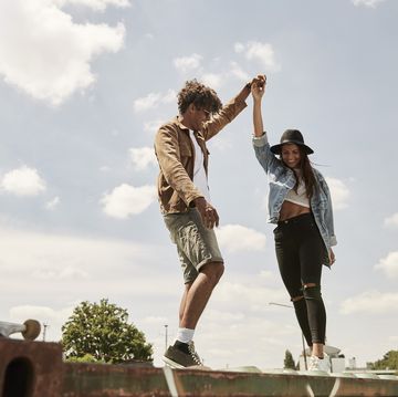 young couple standing on wall, raising arms