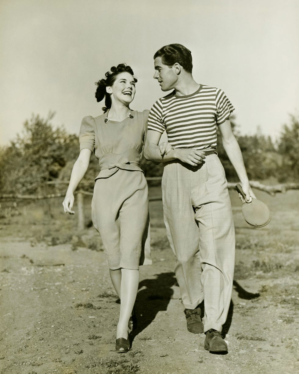 young couple strolling in field arm in arm, bw