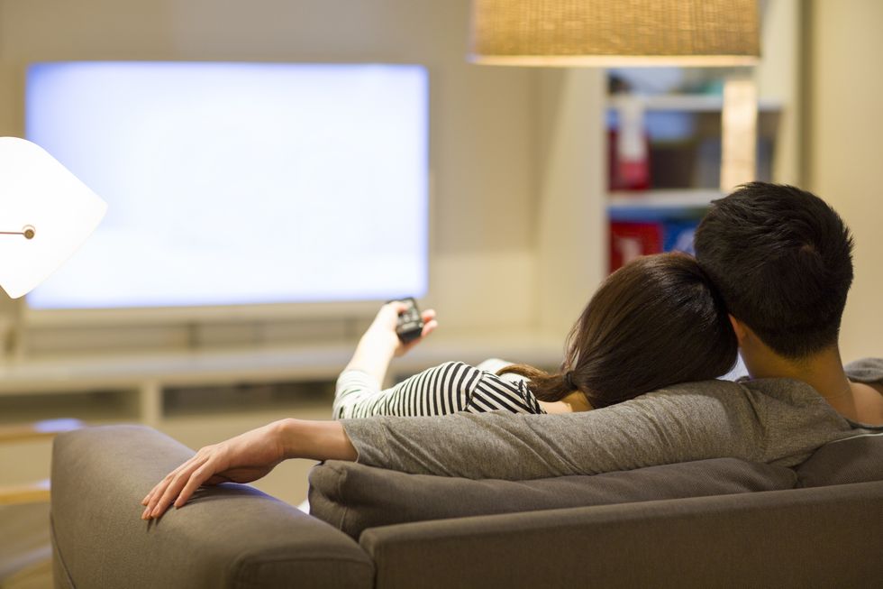 young couple watching tv on living room sofa
