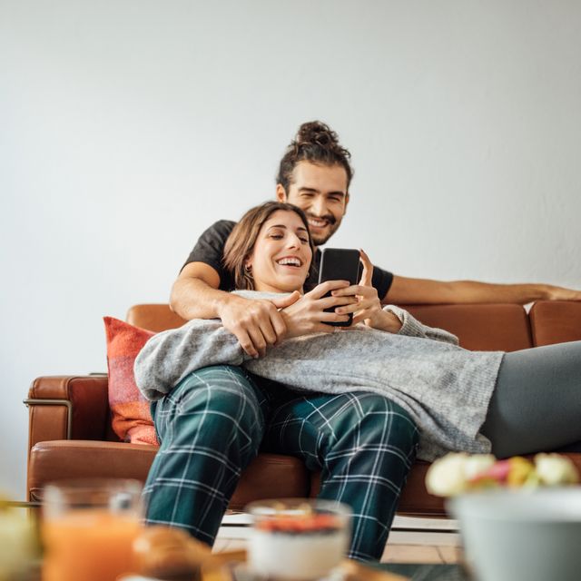 Young couple with smart phone relaxing on sofa