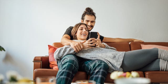 Young couple with smart phone relaxing on sofa