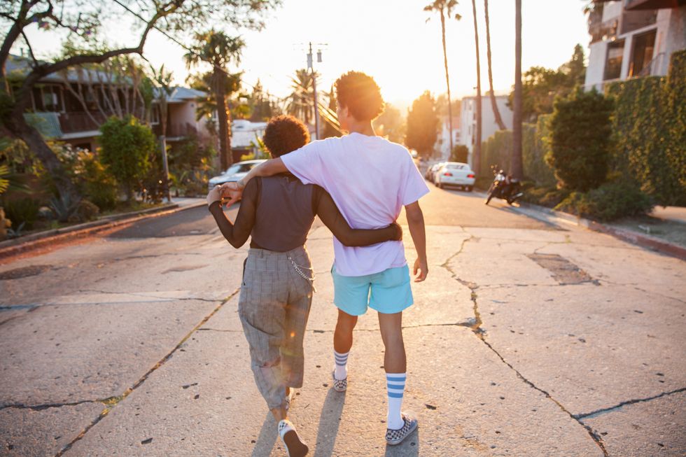 young couple with their arms around each other walking down street