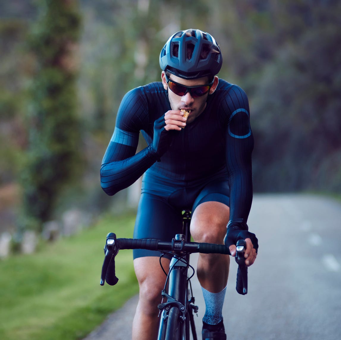 young cyclist riding bicycle and eating snack bar outdoors