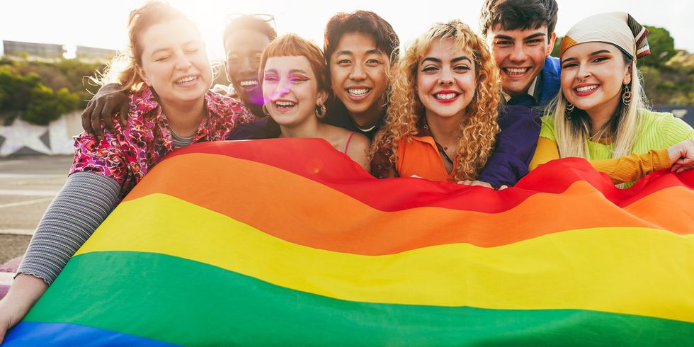 young diverse people having fun holding lgbt rainbow flag outdoor   focus on center blond girl