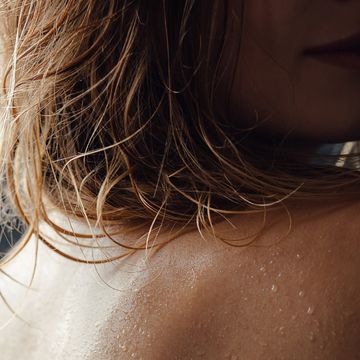 young european woman in shower close up back with water drops